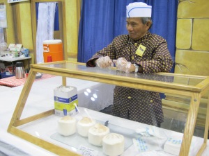 Man at the Cambodia booth selling fresh coconut water.